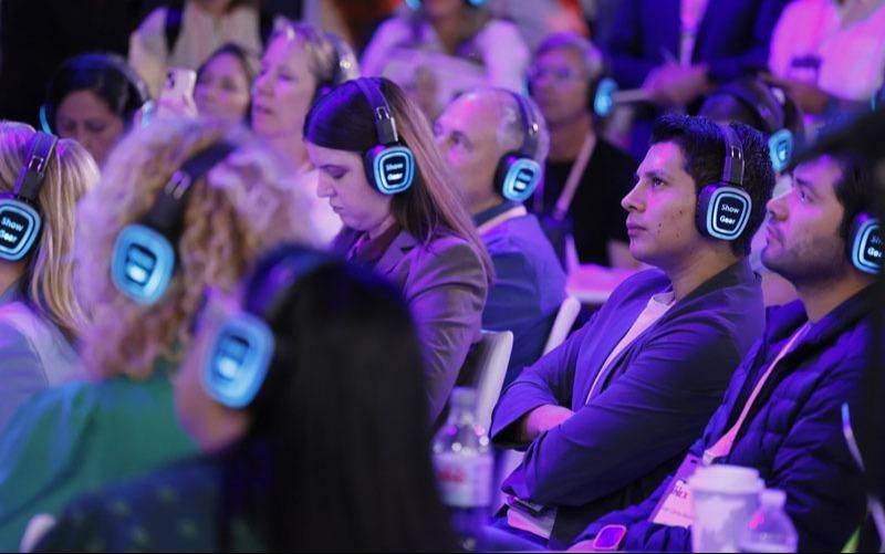 Audience looking towards the stage during an education session wearing glowing headphones