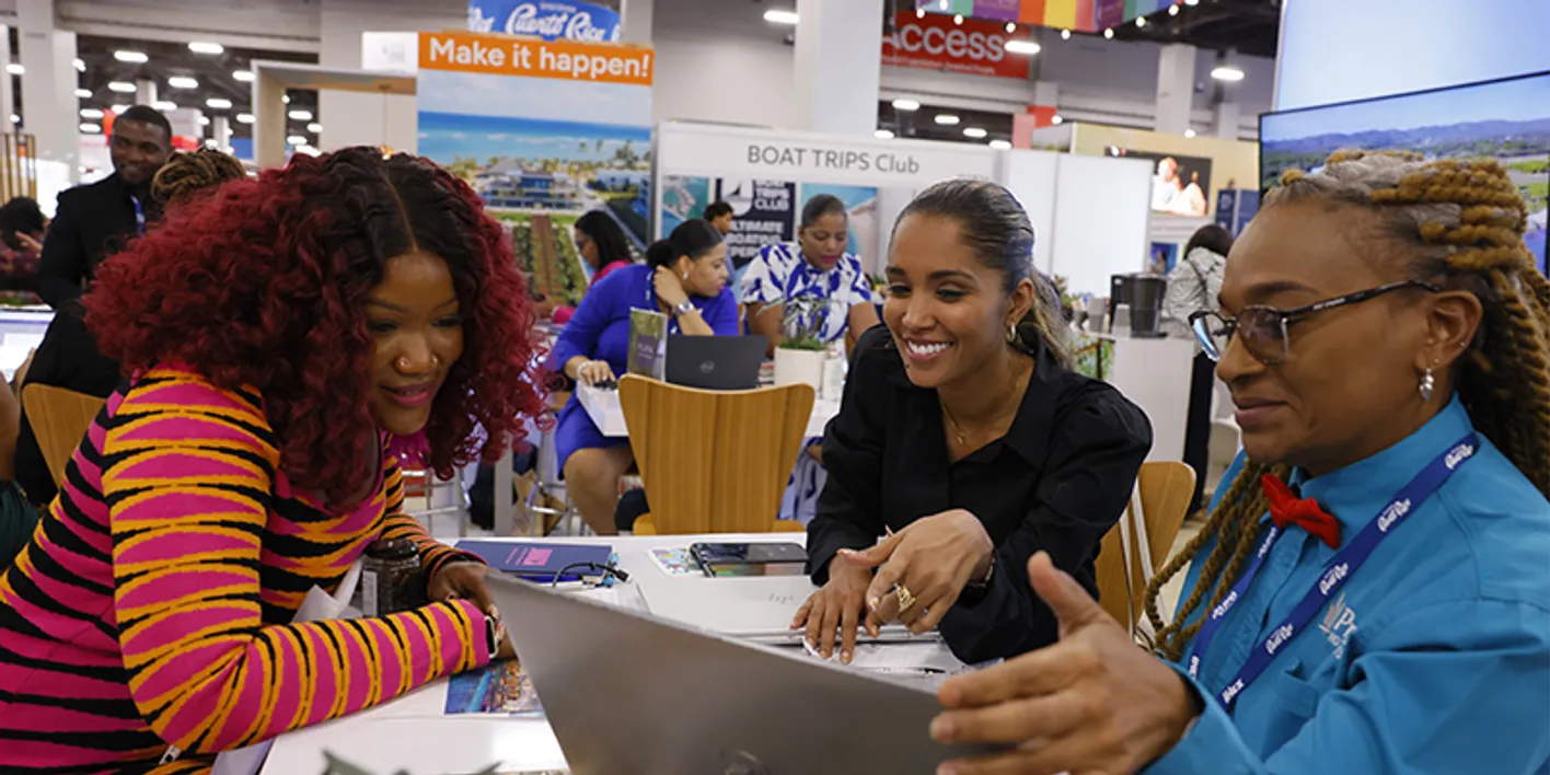 Attendees networking on the IMEX tradeshow floor while viewing their laptops