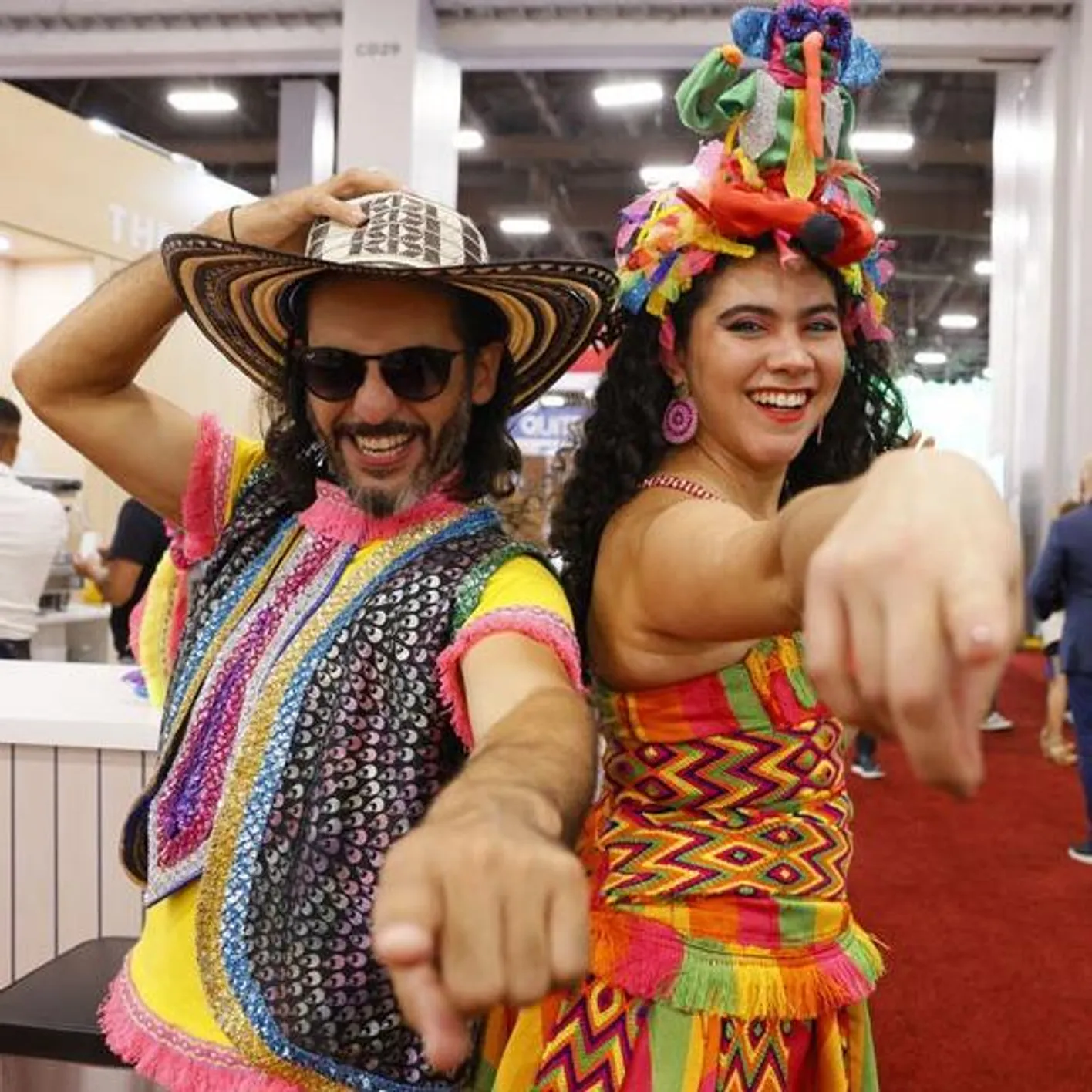 Two people in traditional costume pointing and smiling at the camera