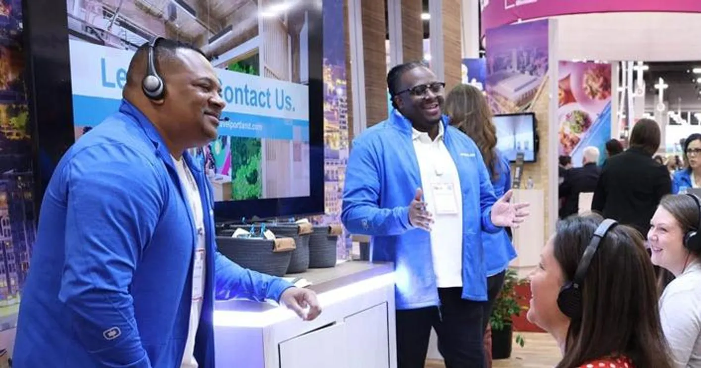 Interactive booth session with two male speakers using headphones to connect with attendees