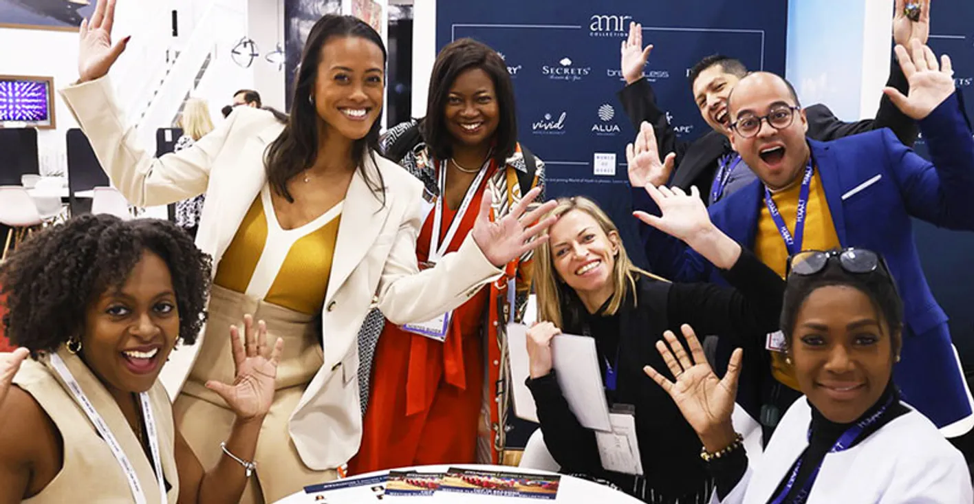 Friendly exhibitors waving to the camera from their booth