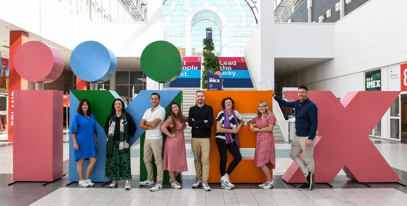 the IMEX sales team in front of IMEX branded lettering