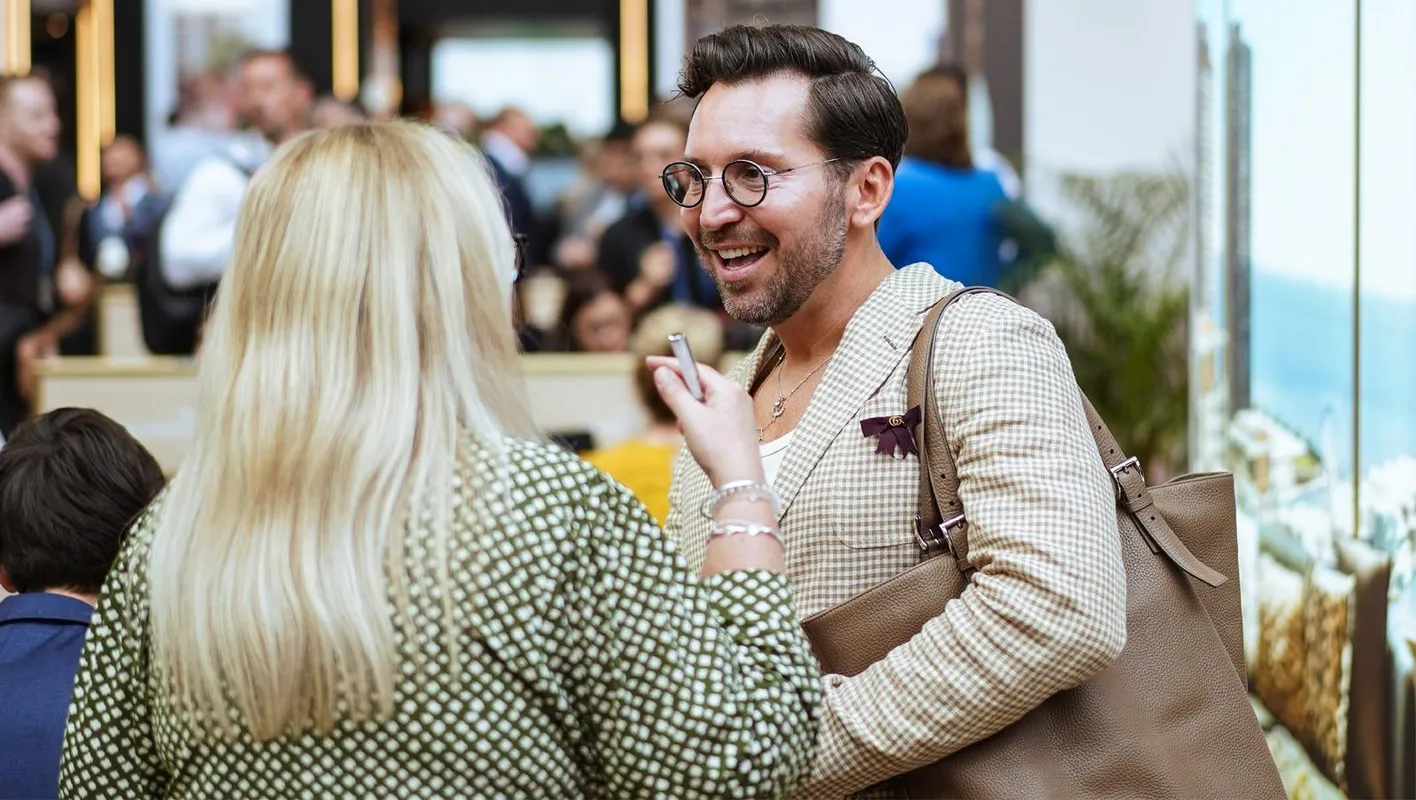 2 people talking at IMEX Frankfurt. A women has her back to the camera. A man in a suit faces it.