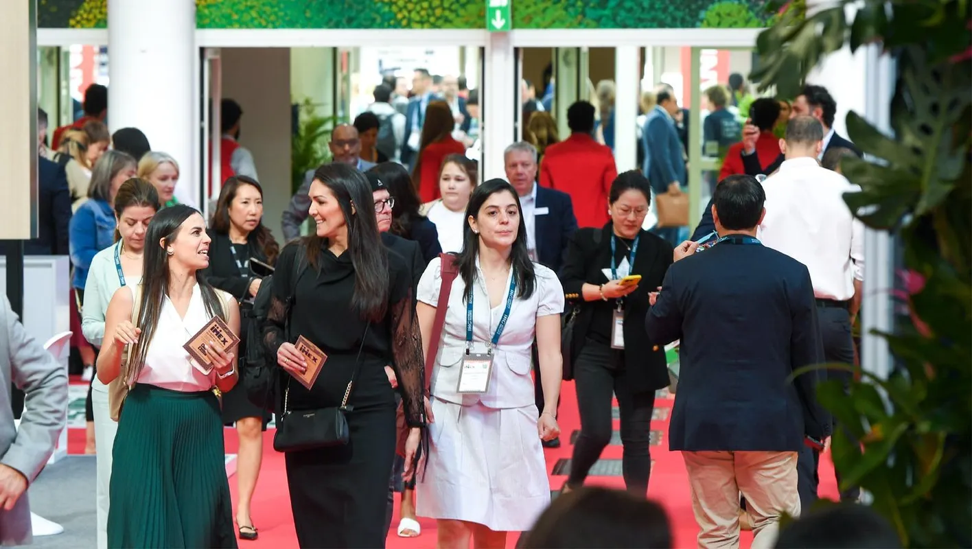 A crowd of people in business casual walk on a red carpet. 