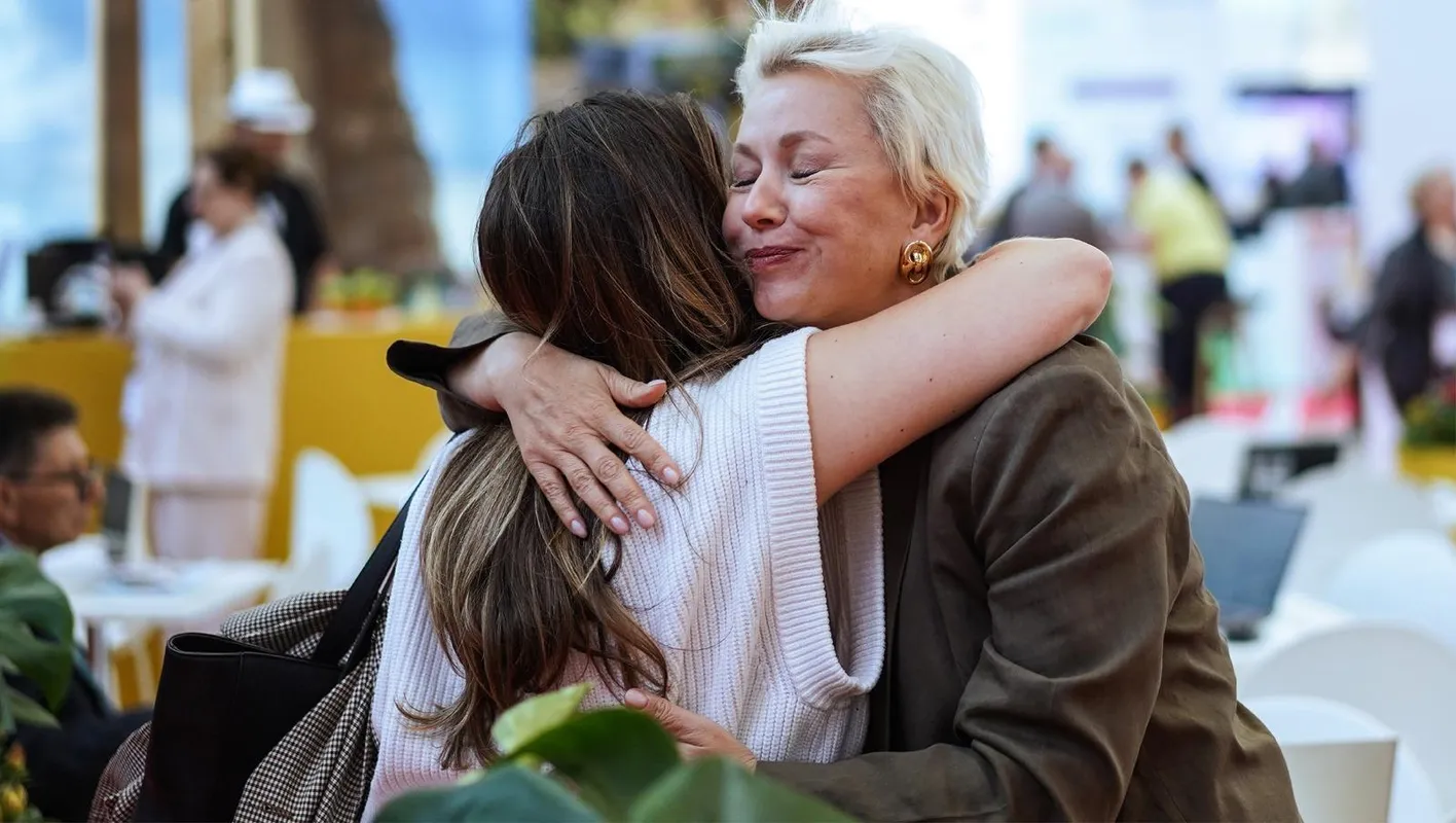 Two attendees hug on IMEX Frankfurt's show floor.