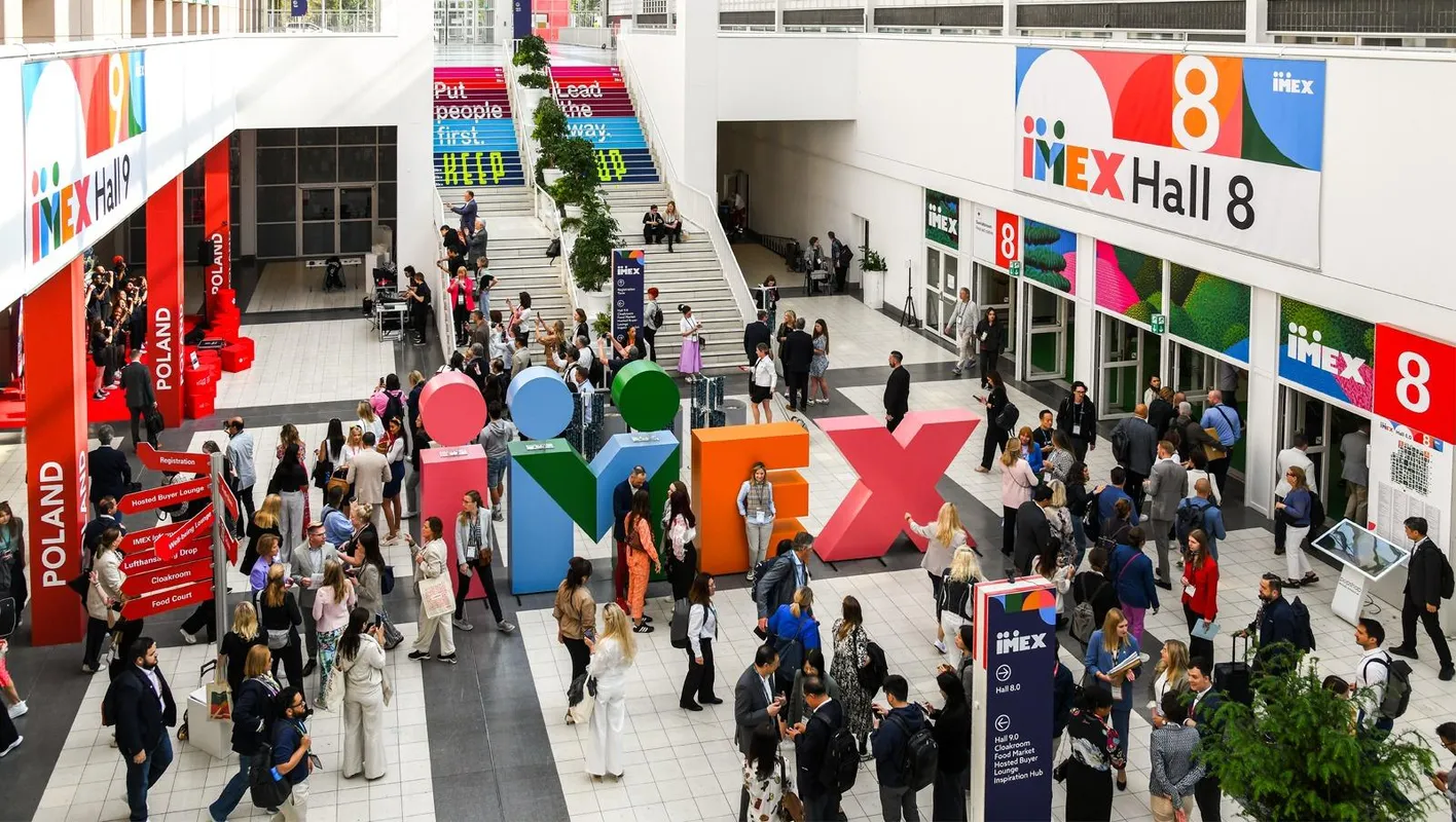 Busy IMEX  Galleria with colorful IMEX letters, stairs and 'Put People First' and 'Hall 8' banner.