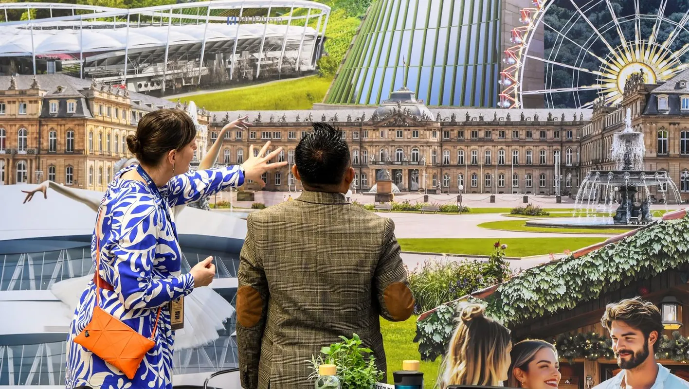 Two people stand with their backs to the camera looking at a photo of a mansion printed on a booth
