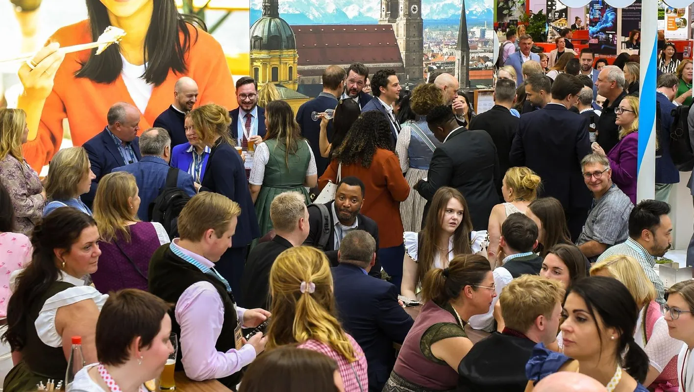 A large crowd of attendees on IMEX show floor in front of booths.