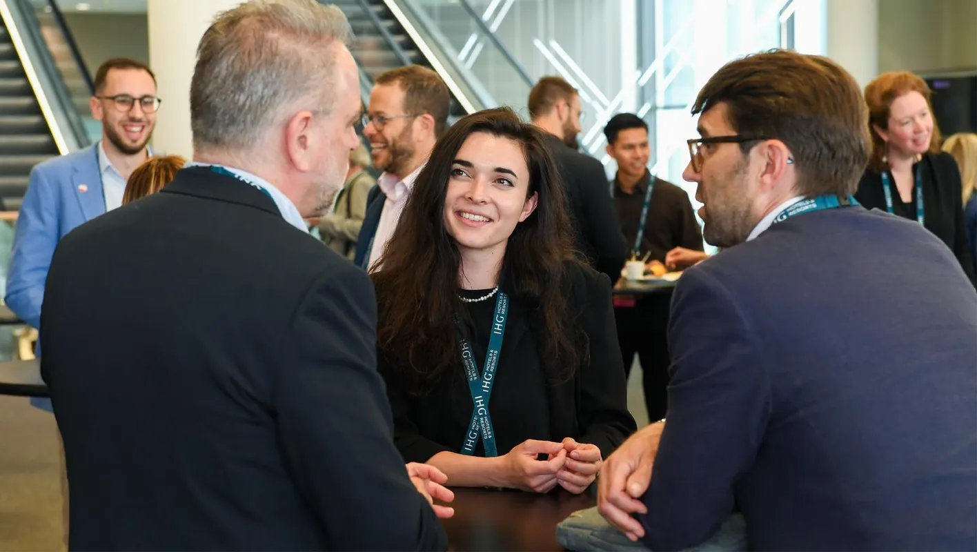 An attendee looks away from the camera smiling at another attendee with their back to the camera.