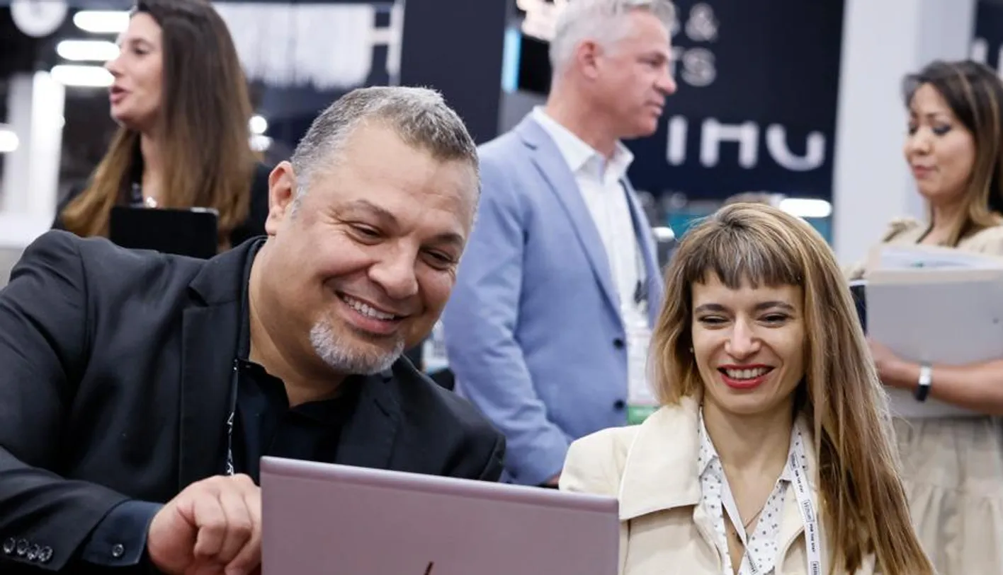 Two people looking at a laptop on the show floor smiling