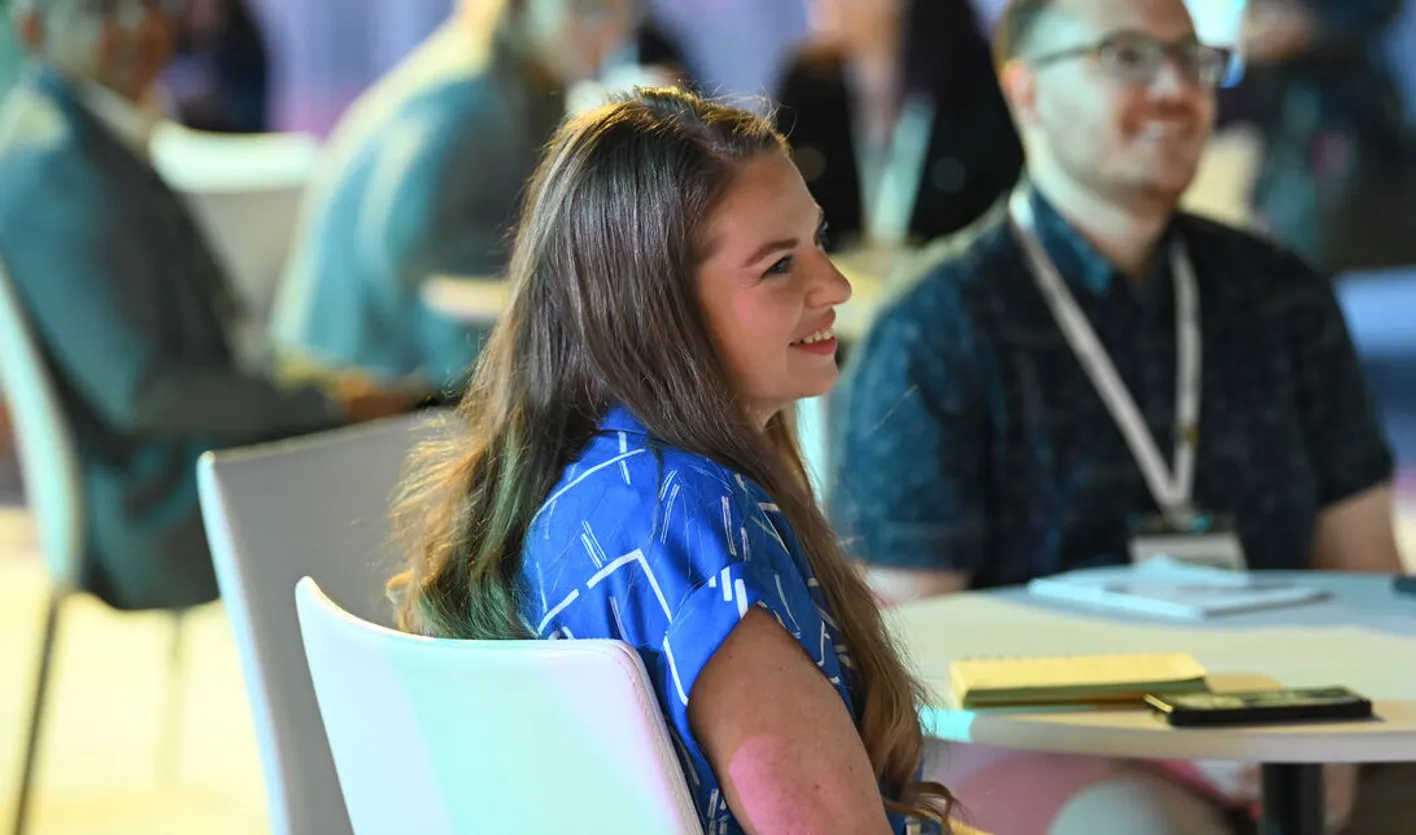 Audience member smiling towards the stage and showing enthusiasm during a corporate session