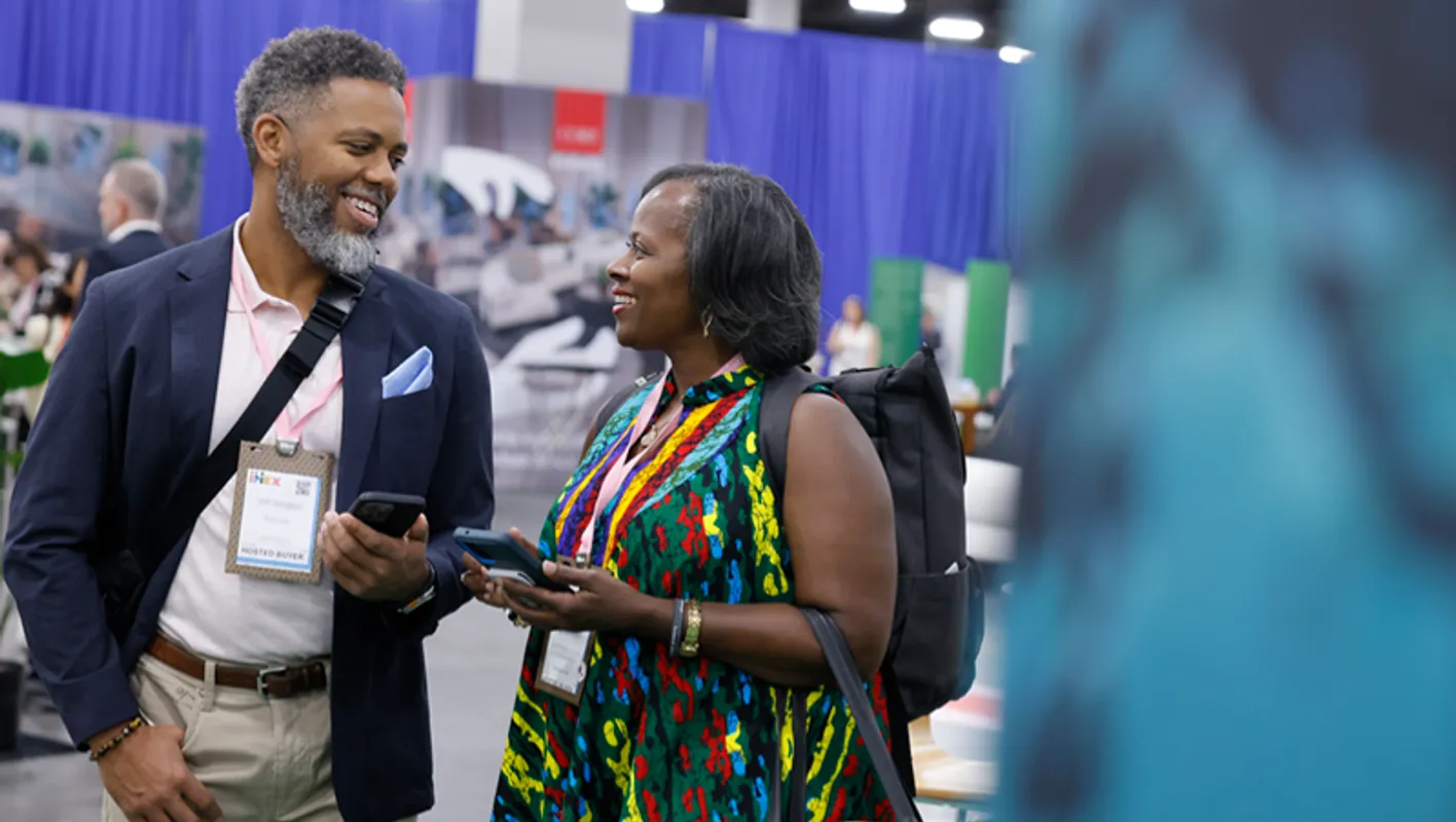 Relaxed face to face standing conversation between two people on the IMEX showfloor