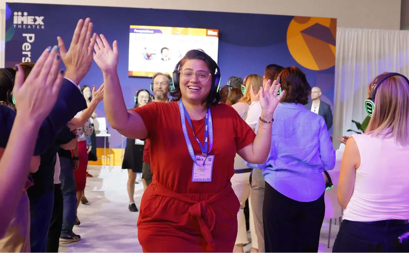Person walking past a crowd high fiving them at the education area, IMEX
