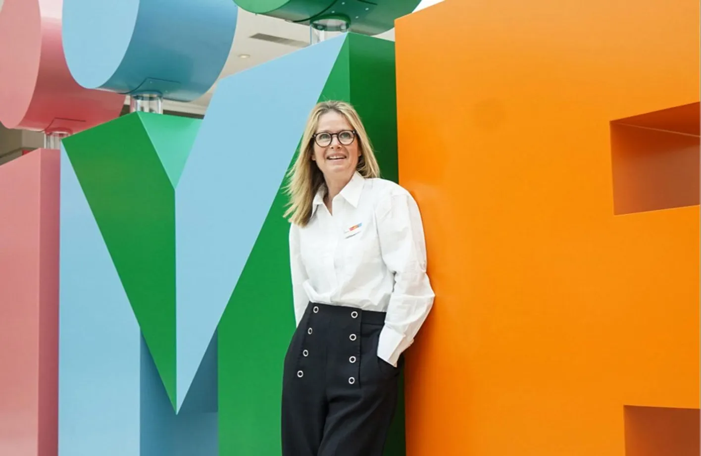 Head of Design, Anna Gyseman stands laughing in an up close shot of the large, IMEX letters.