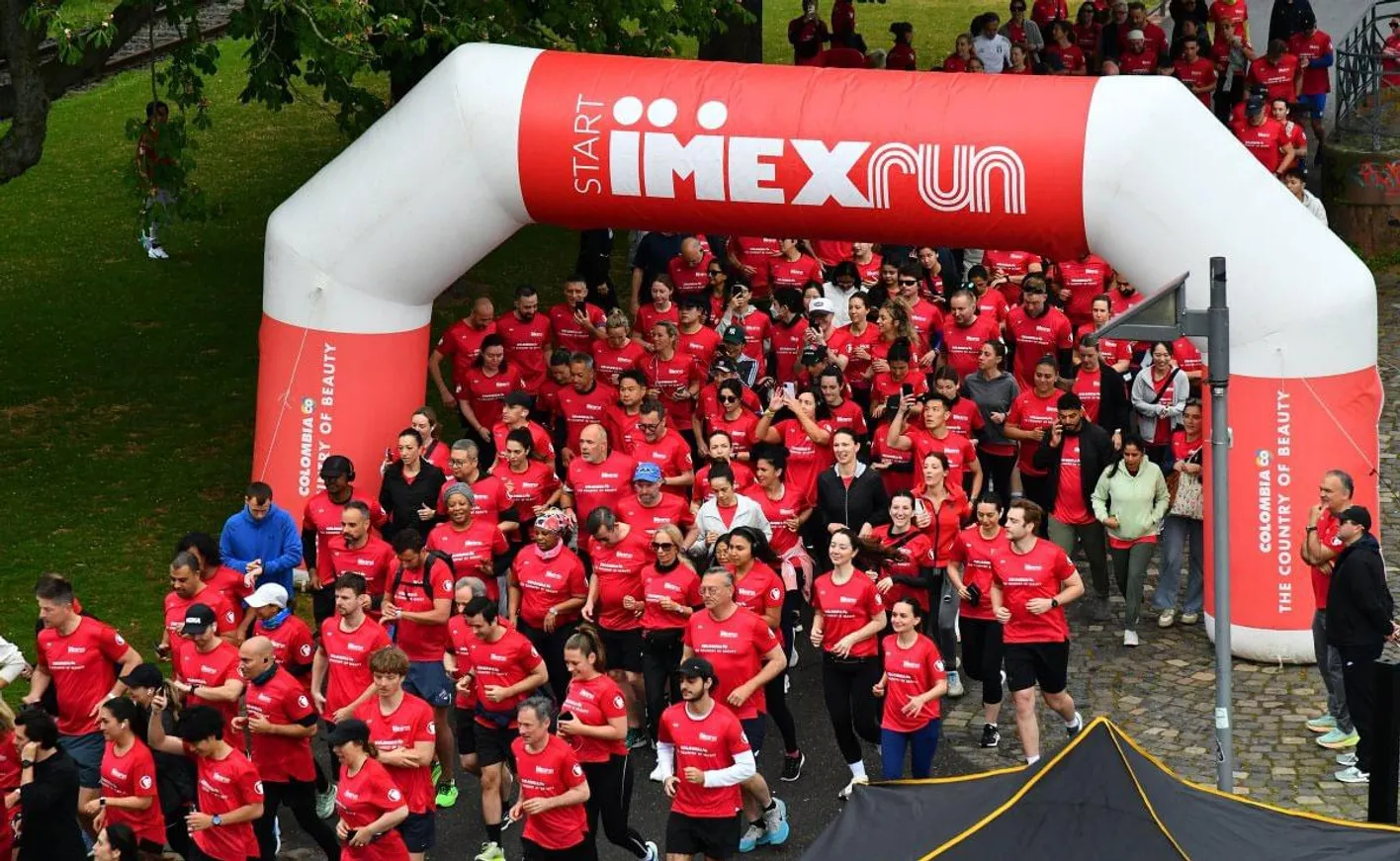 IMEXrunners making strides over a bridge in Frankfurt, smiling with hands in the air
