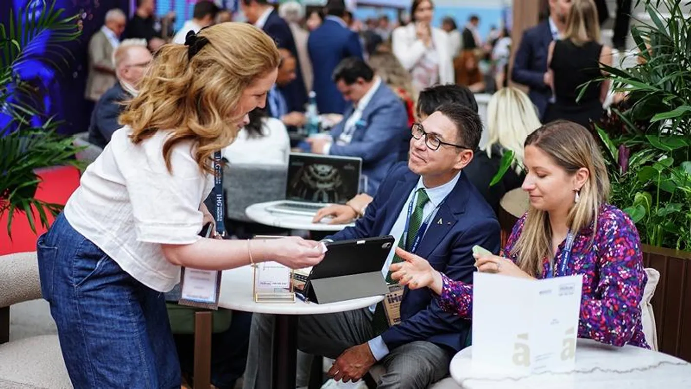 Teilnehmende der IMEX Frankfurt beim Networking an einem Tisch auf der Messefläche