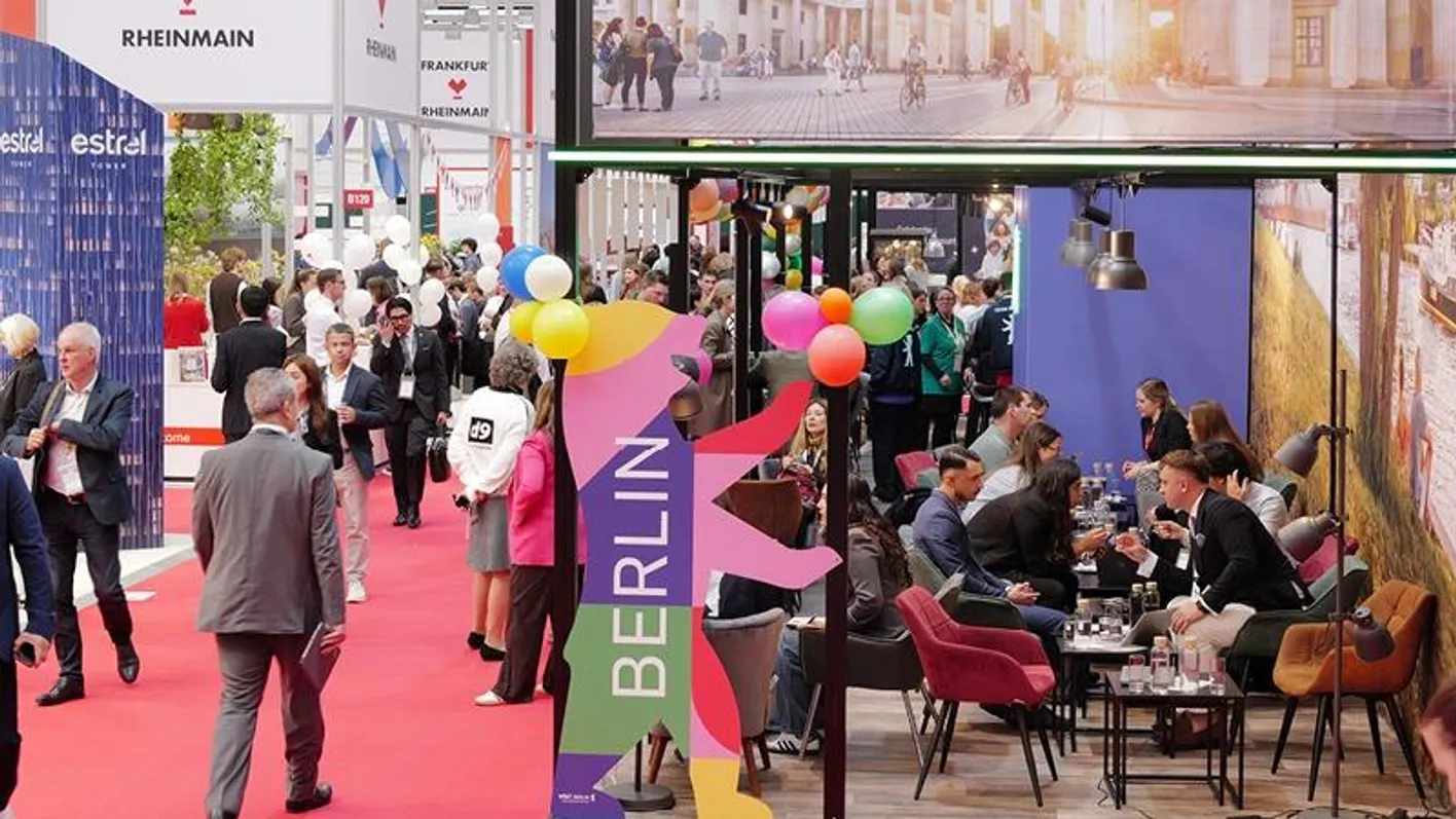 People walking near booths and seated for their meetings on the show floor.