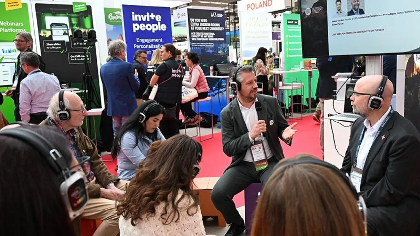 A group presentation taking place at a booth, they are communicating wearing lit up headphones.