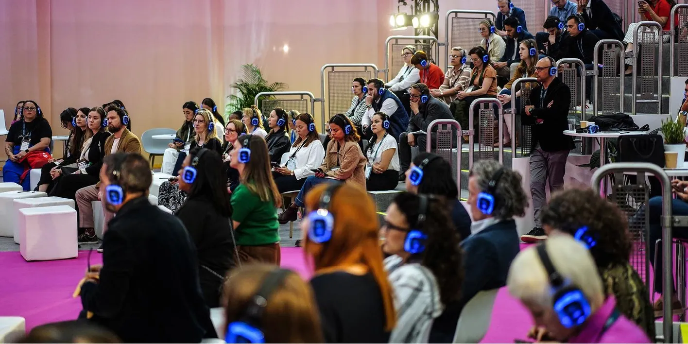 Attendees wearing headphones on tiered seating during an education session at IMEX Frankfurt.