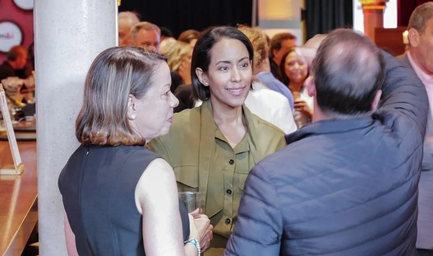 Three attendees stand smiling and conversing at Site Nite.