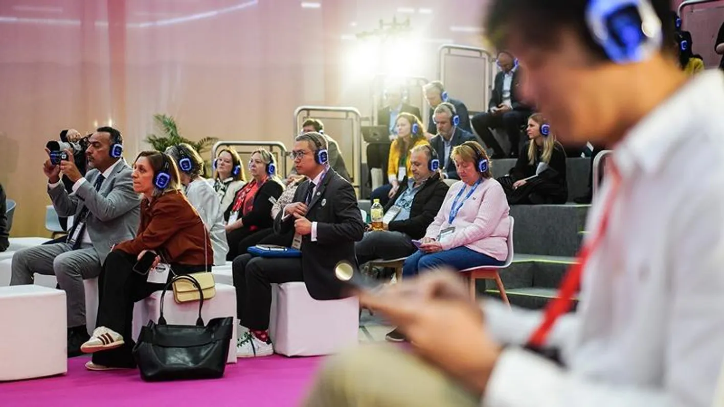Attendees seated with headphones at an education session on tiered seating.