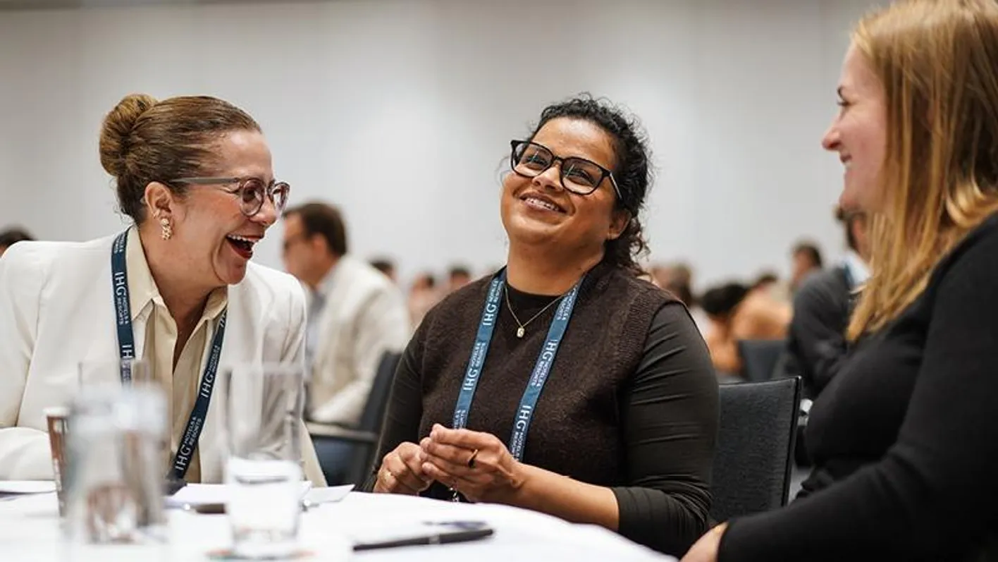 Three people conversing on a roundtable while smiling during Exclusively Corporate