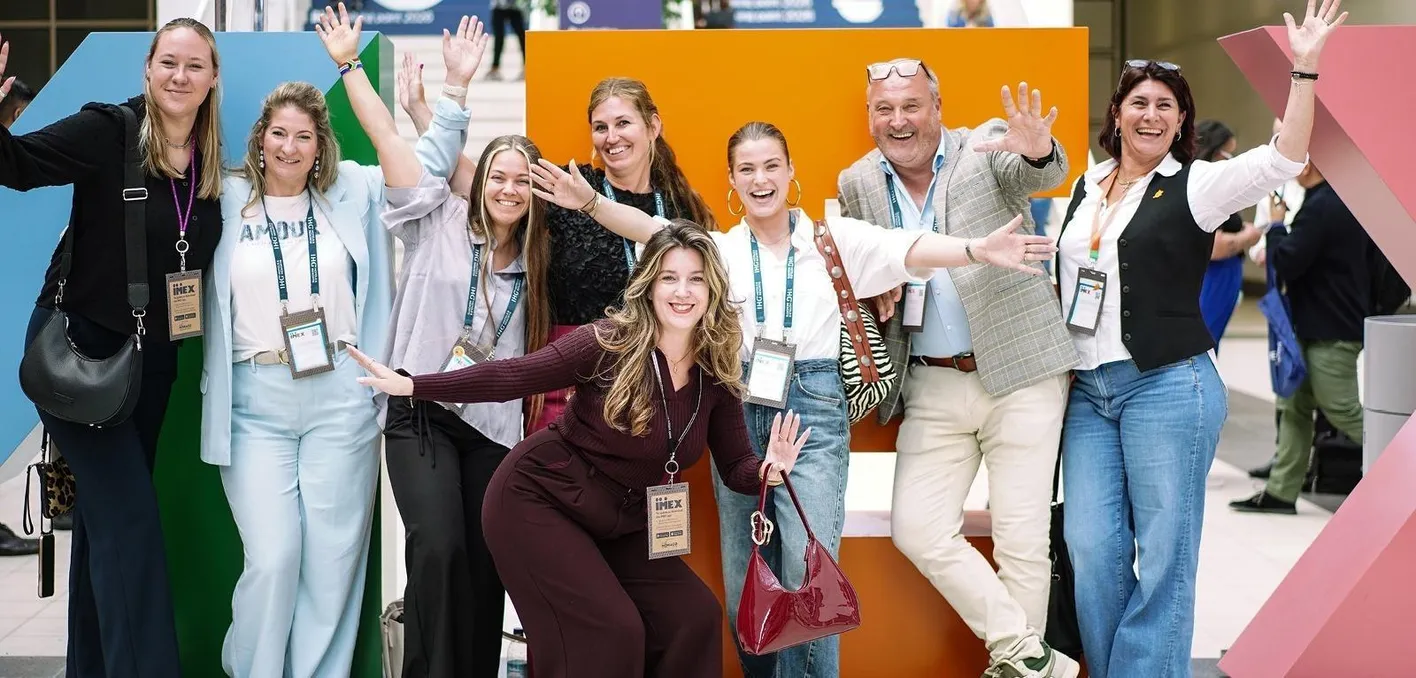 A group of people posing at IMEX Frankfurt's busy Galleria with large IMEX letters