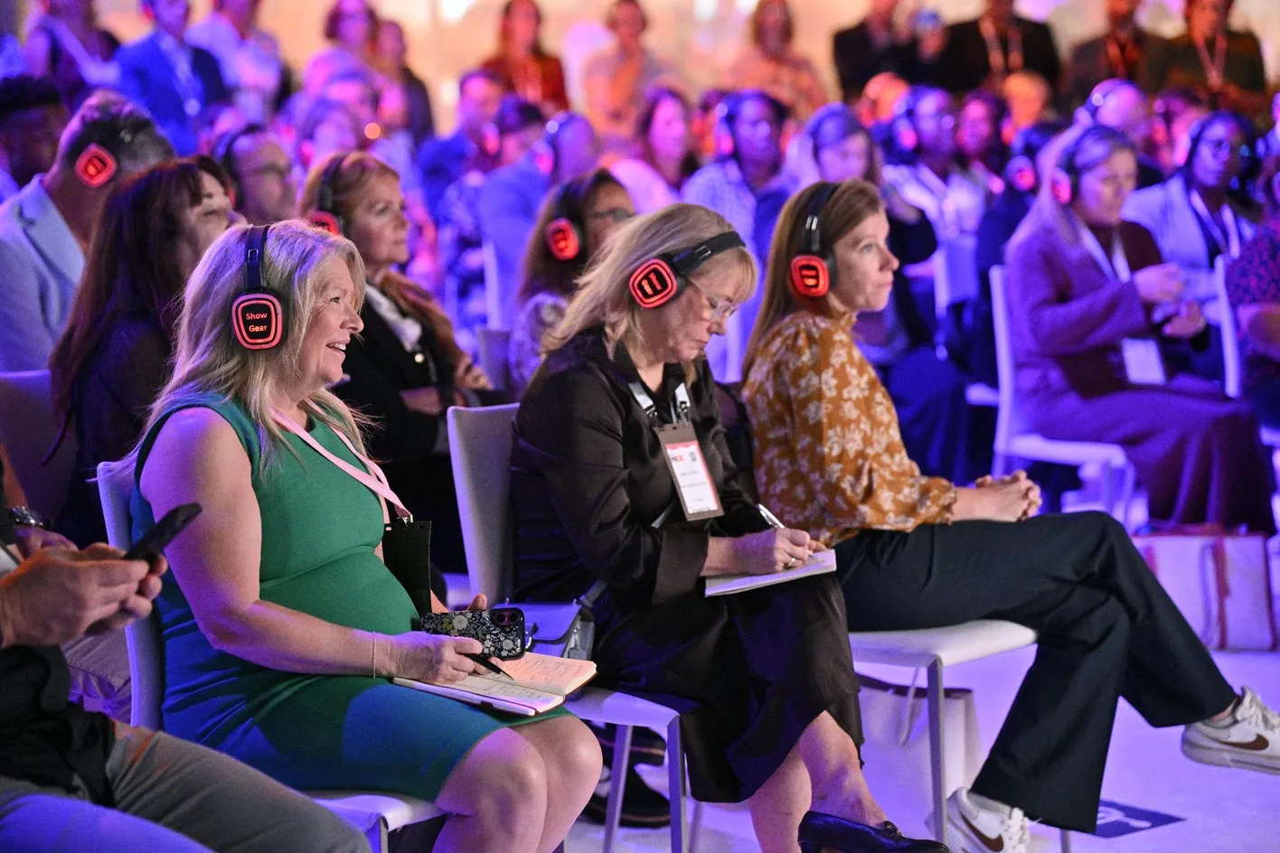 Attendees listening with headphones at an IMEX America education session
