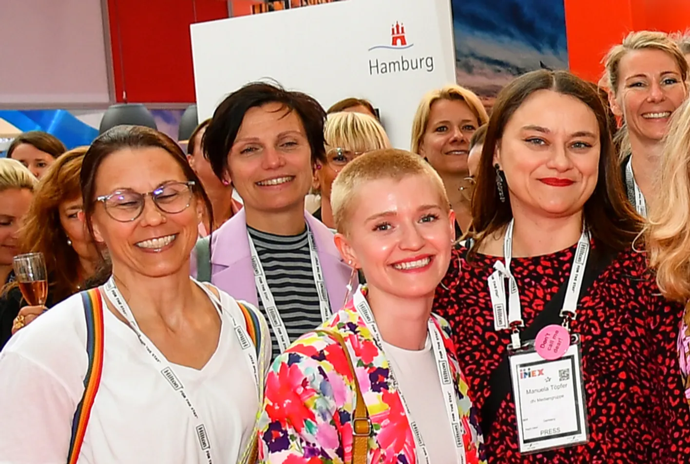 A group of attendees in colorful business casual clothing stand smiling at the camera.