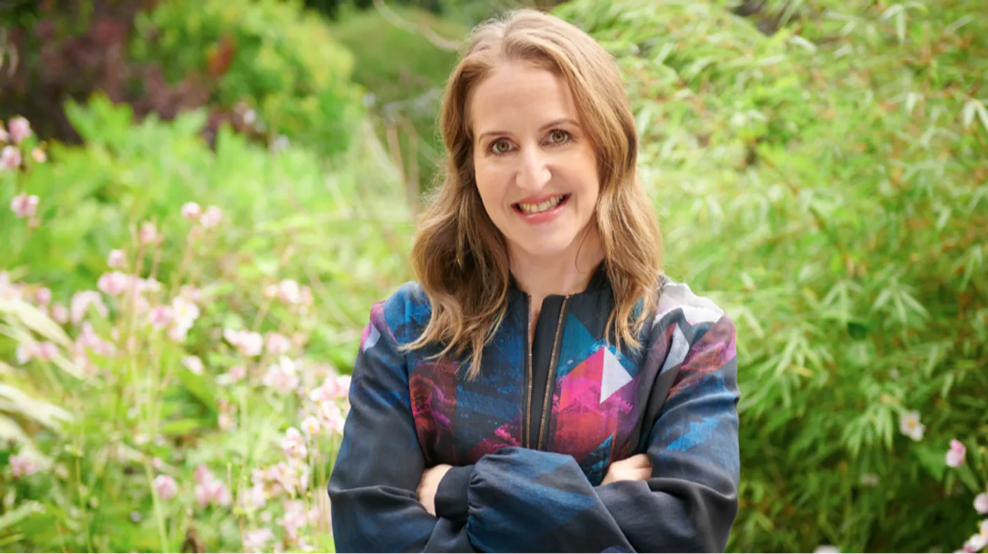 IMEX's CEO, Carina Bauer, stands smiling at the camera with her arms crossed across her chest.