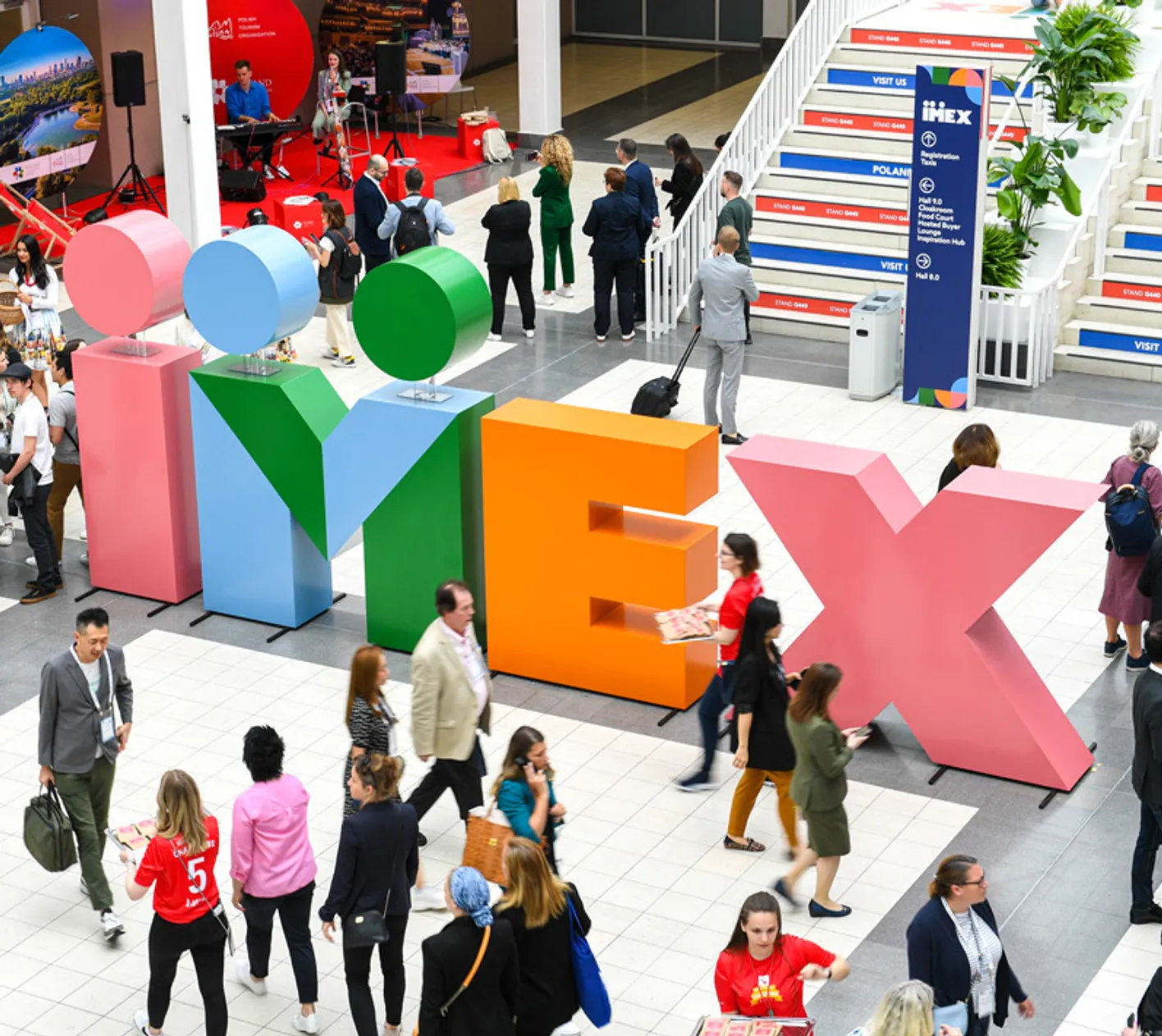 Galleria at IMEX Frankfurt. There's large IMEX letters, stairs and a crowd of attendees.