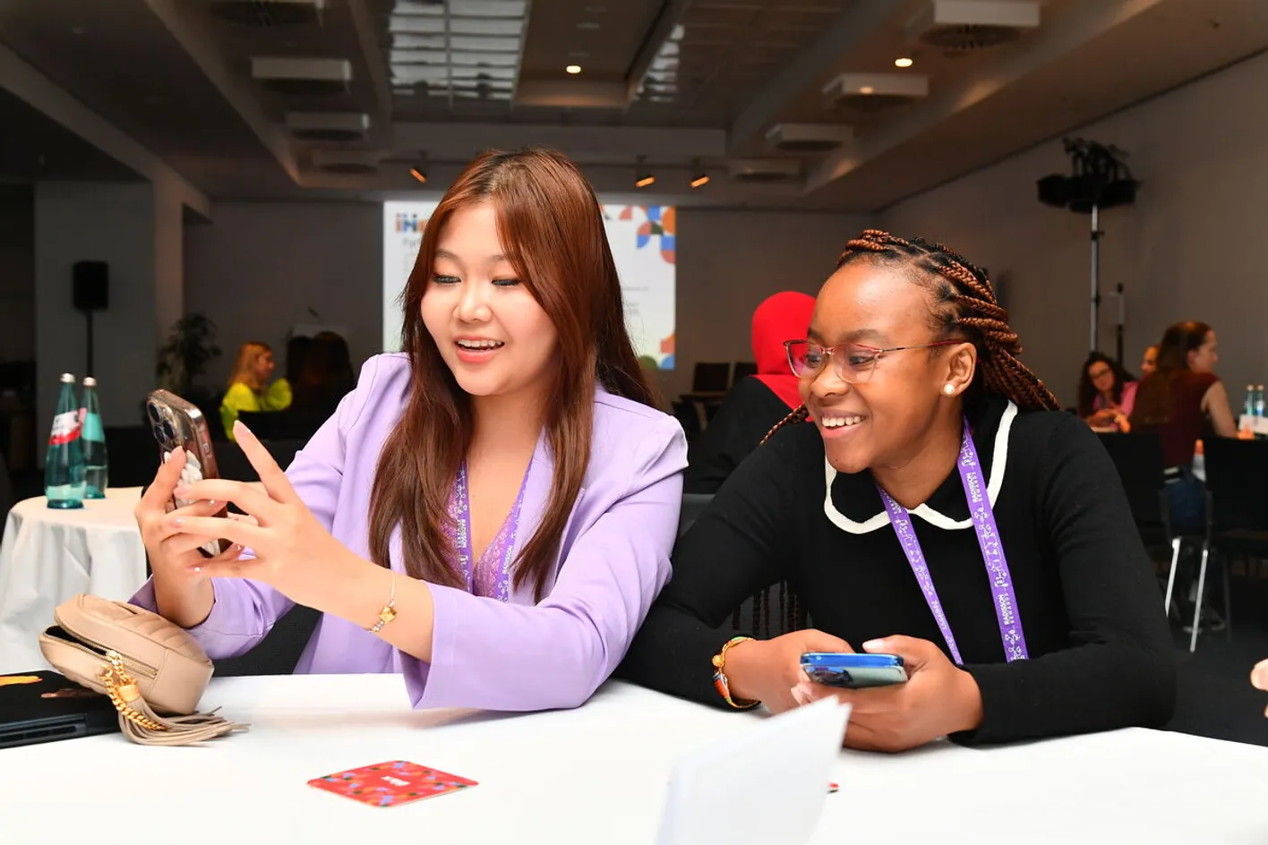 Two attendees sat at table sharing phone screen in conference room