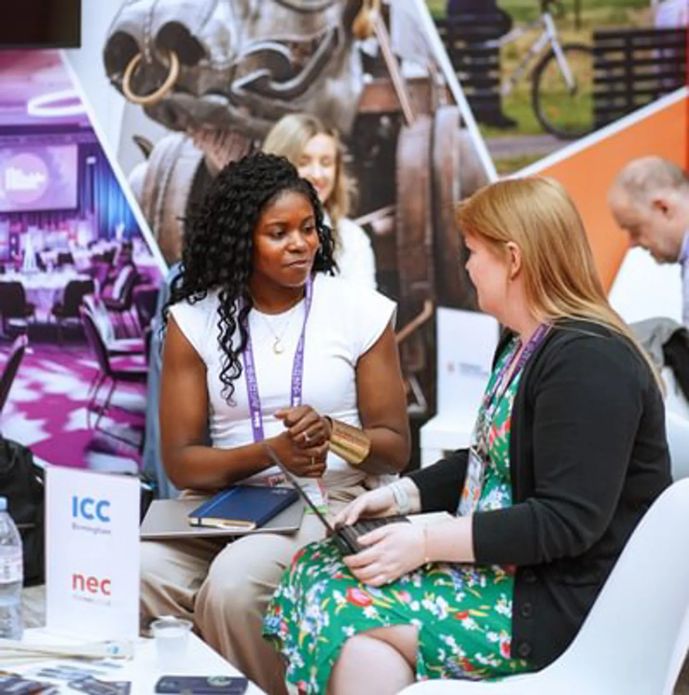 Two attendees sat looking at each oter in a meeting in a booth on IMEX Frankfurt's show floor.