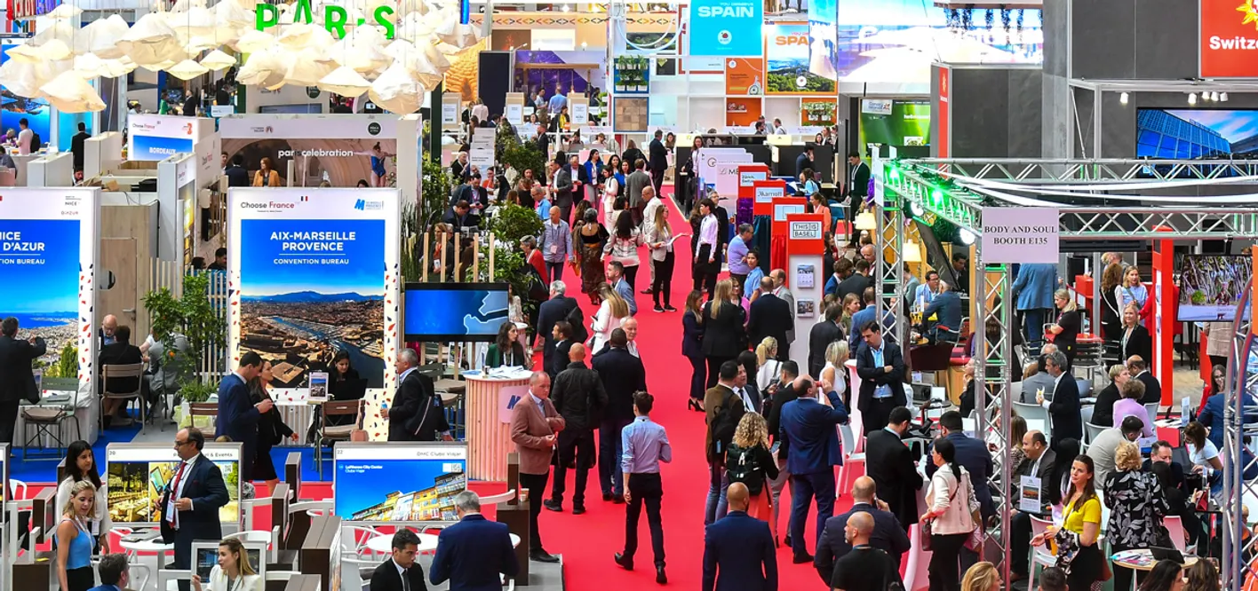 Bird's eye view of IMEX Frankfurt's show floor. There's a red carpet aisle and a crowd of attendees.