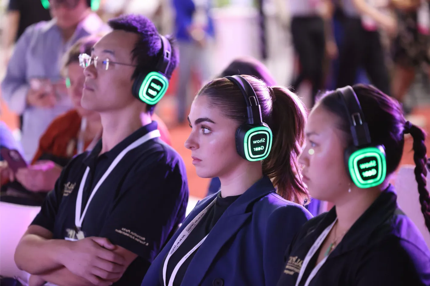 Group of three education attendees from varied backgrounds listening with glowing headphones