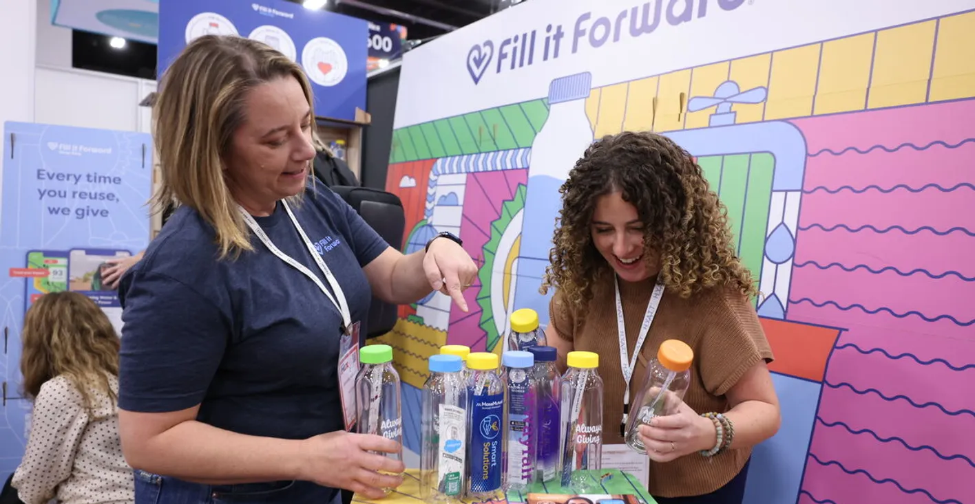 People standing at a fill it forward recyclable bottle booth