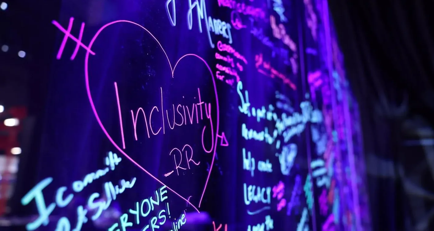 Blackboard with neon writing with the words inclusivity in a heart