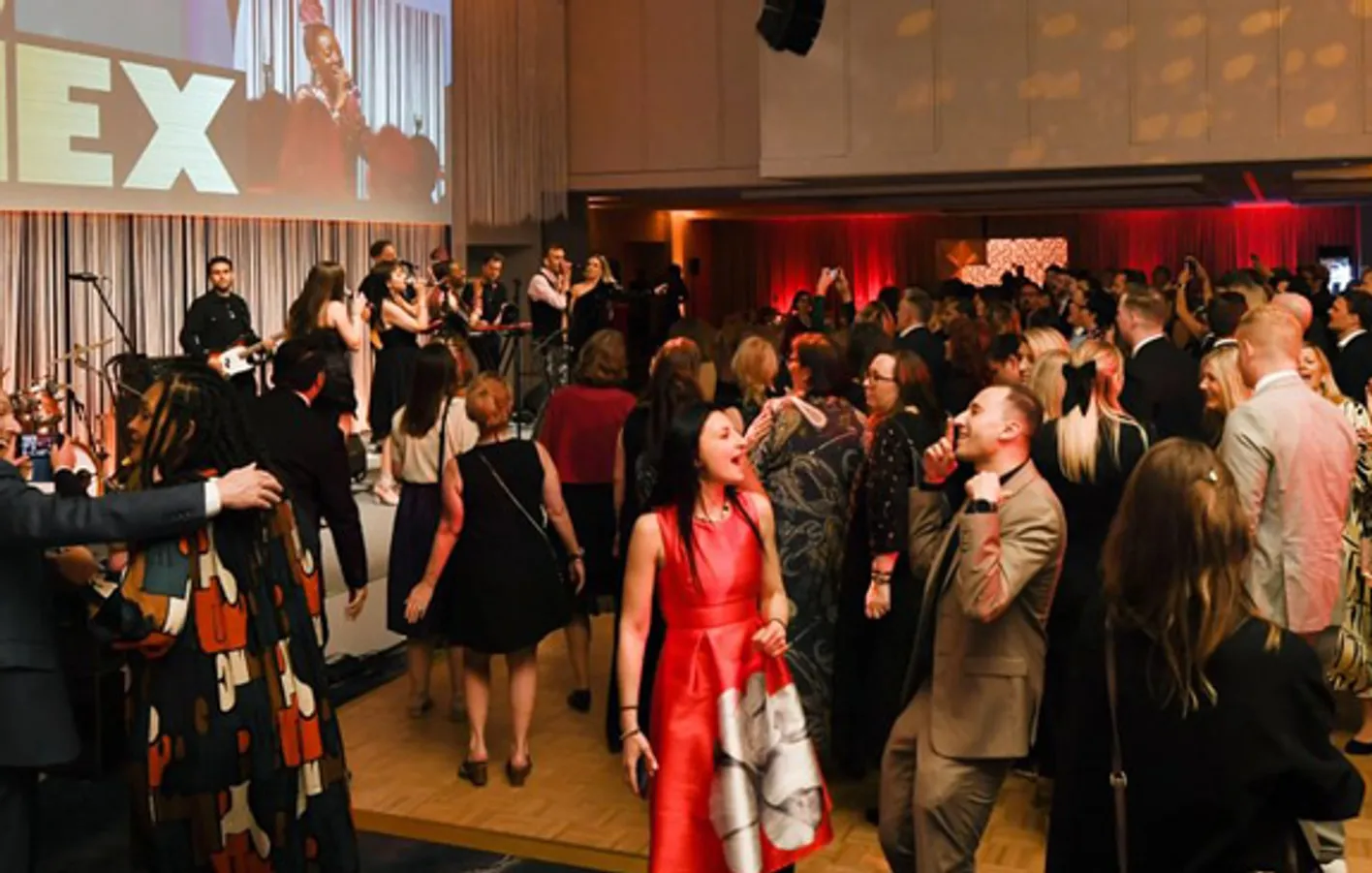 A crowd of IMEX attendees dancing in front of a band