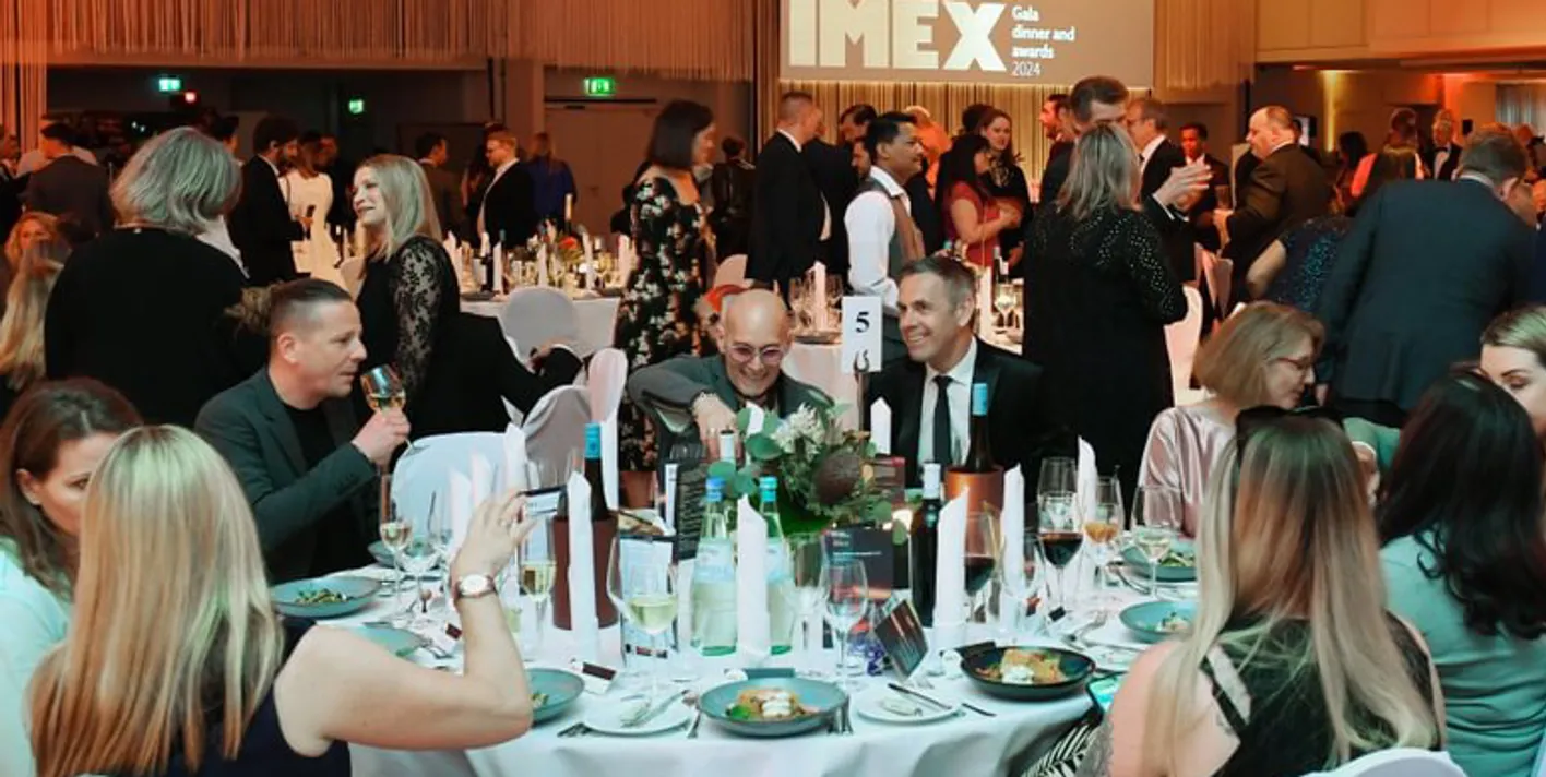 Gala Dinner attendees sit at a round table eating dinner. There's candles on the table