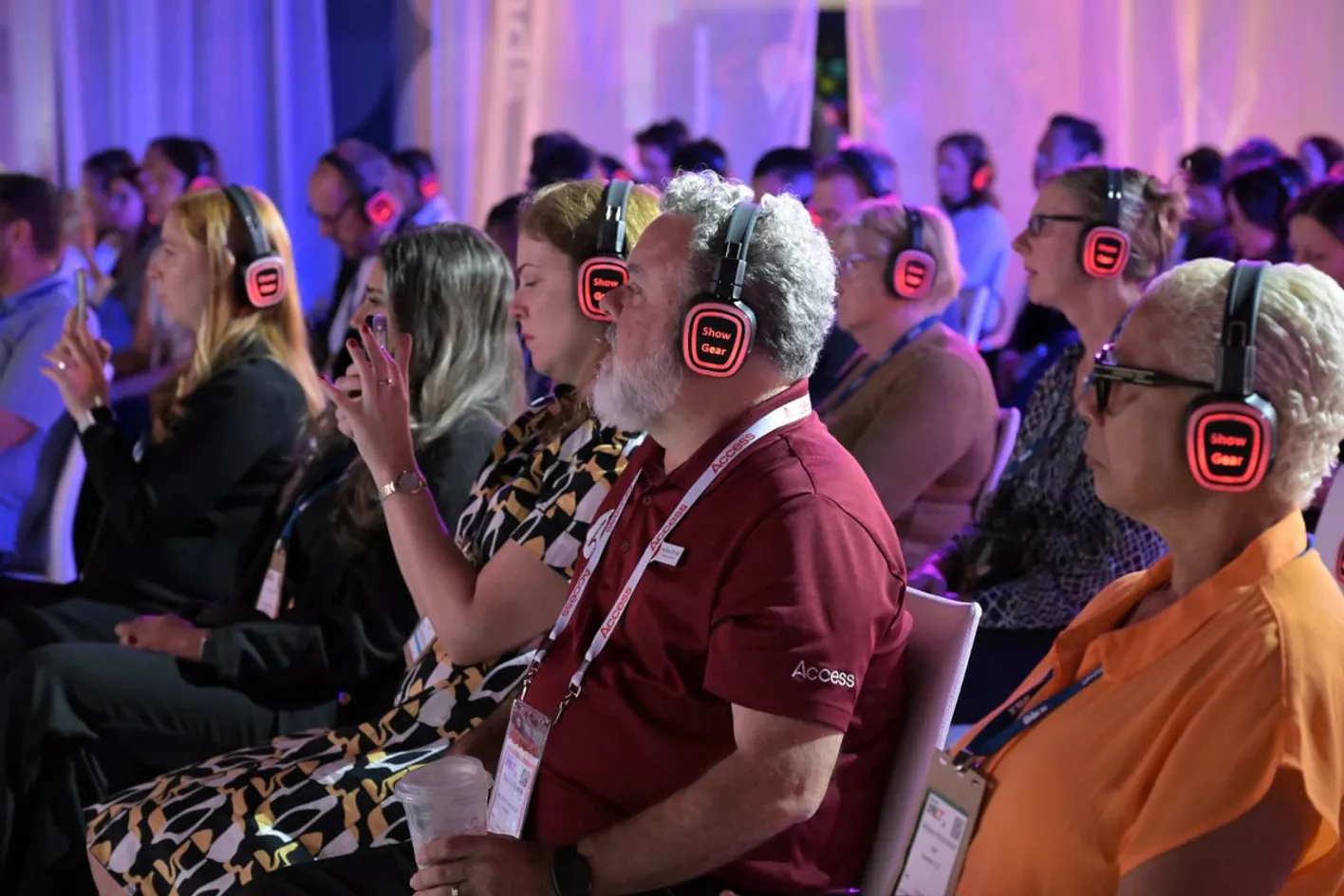 Audience looking towards the stage during an education session wearing glowing headphones