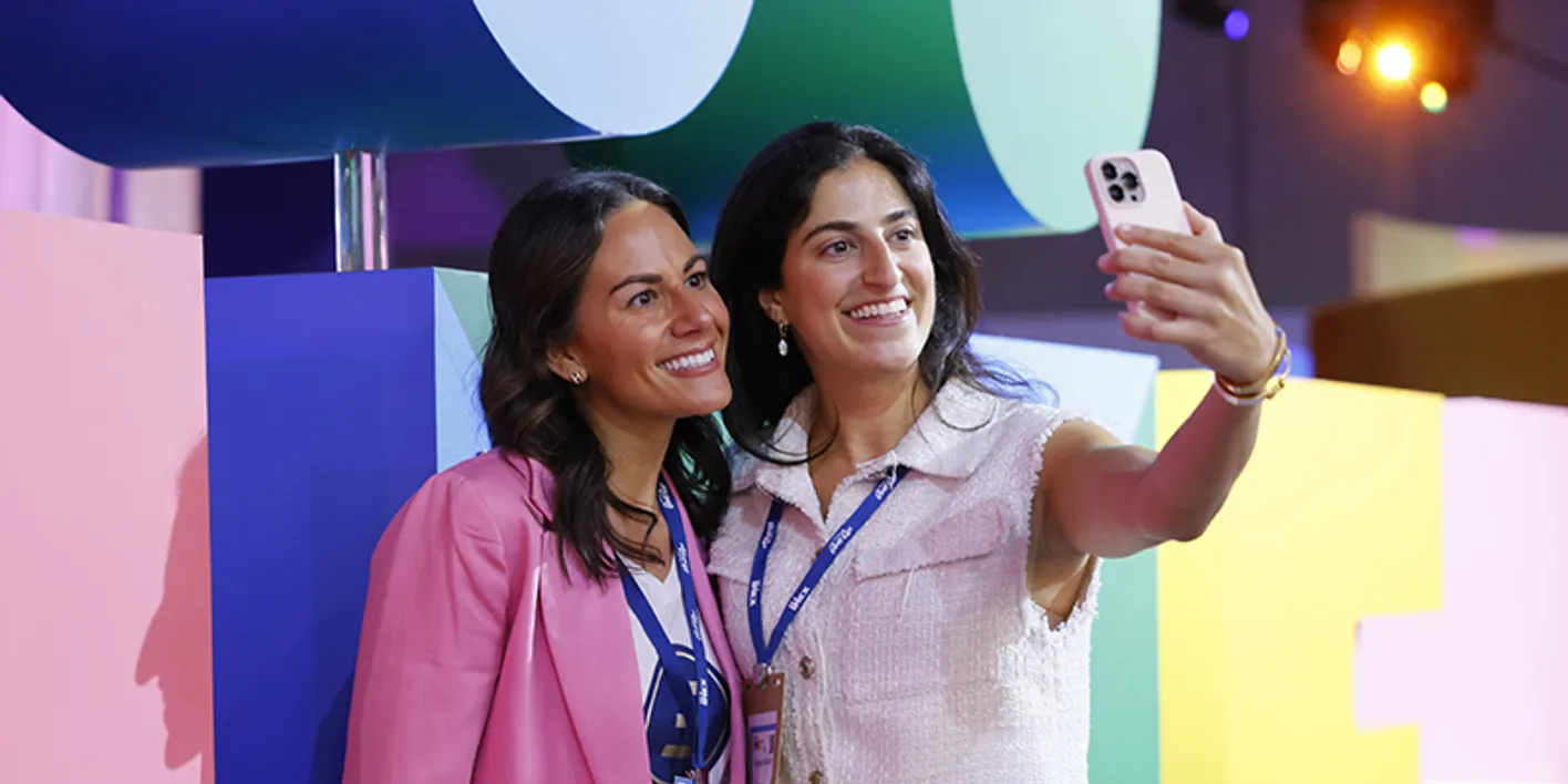 Event professionals taking a selfie in front of IMEX signage