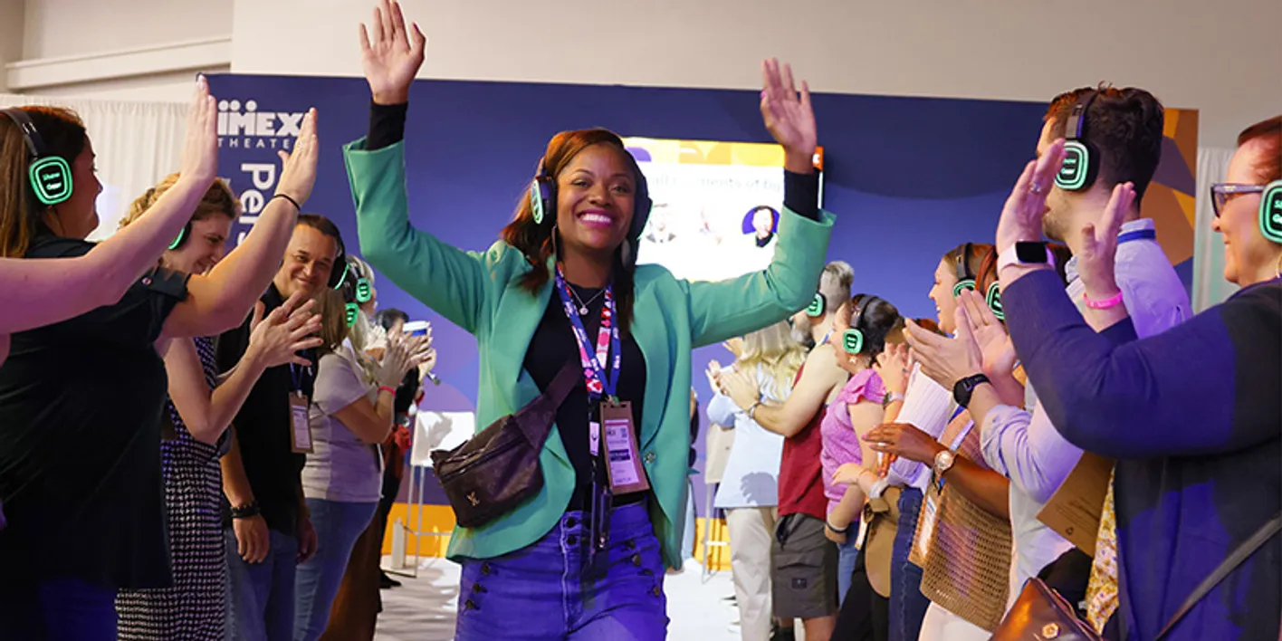 Smiling attendee high-fiving the crowd while walking through the education area