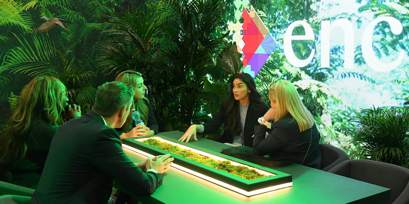 Exhibitors meeting buyers at a green leafy booth at IMEX