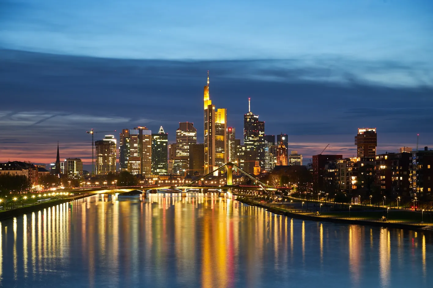 A night time view of Frankfurt's skyline including the river and a bridge