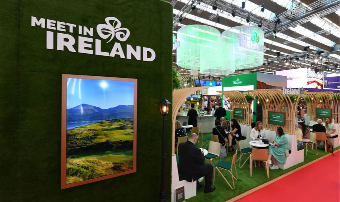 Green Meet Ireland booth with people sat at tables talking and having meetings on the show floor.