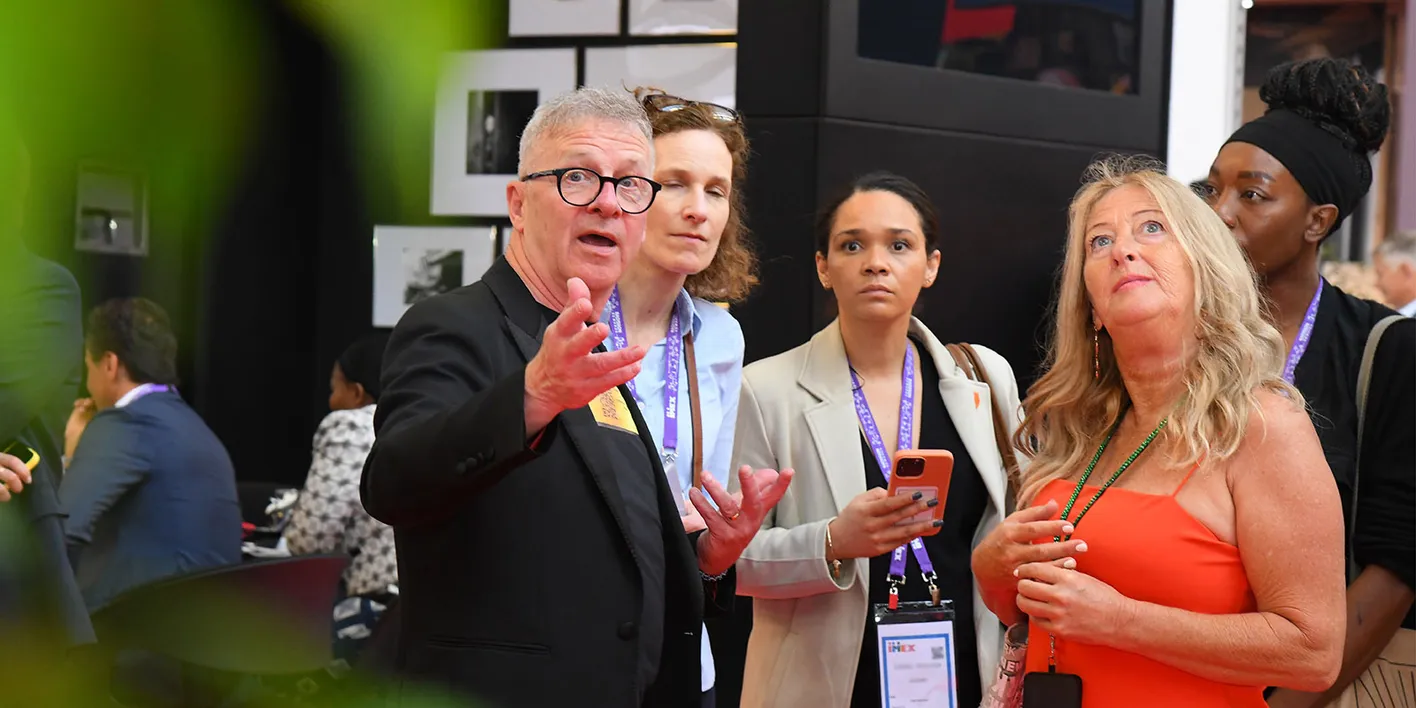 Attendees on a tour of IMEX's show floor. They're staring intently beyond the camera.