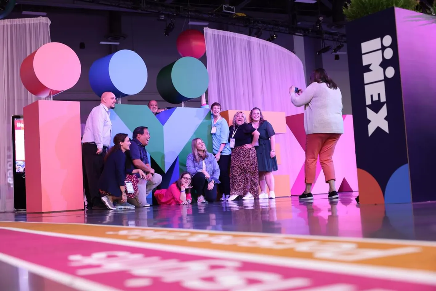 Group photo of meeting events professionals in front of IMEX signage