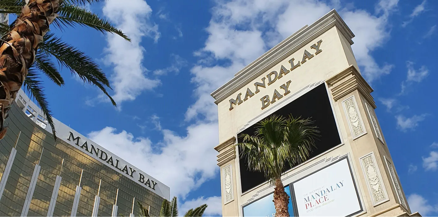 Mandalay Bay gold building and signage against a blue sky and palm tree