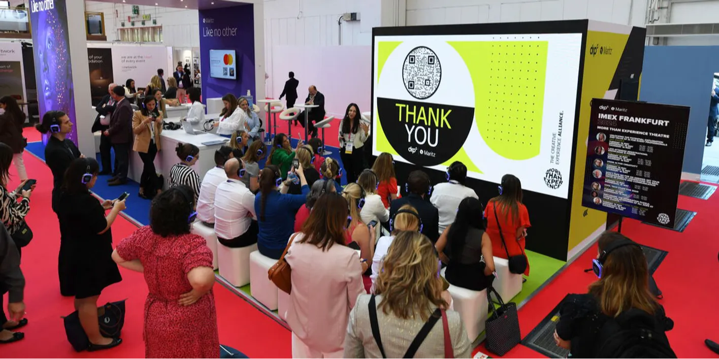 crowd of professionals engaging in booth presentations at IMEX