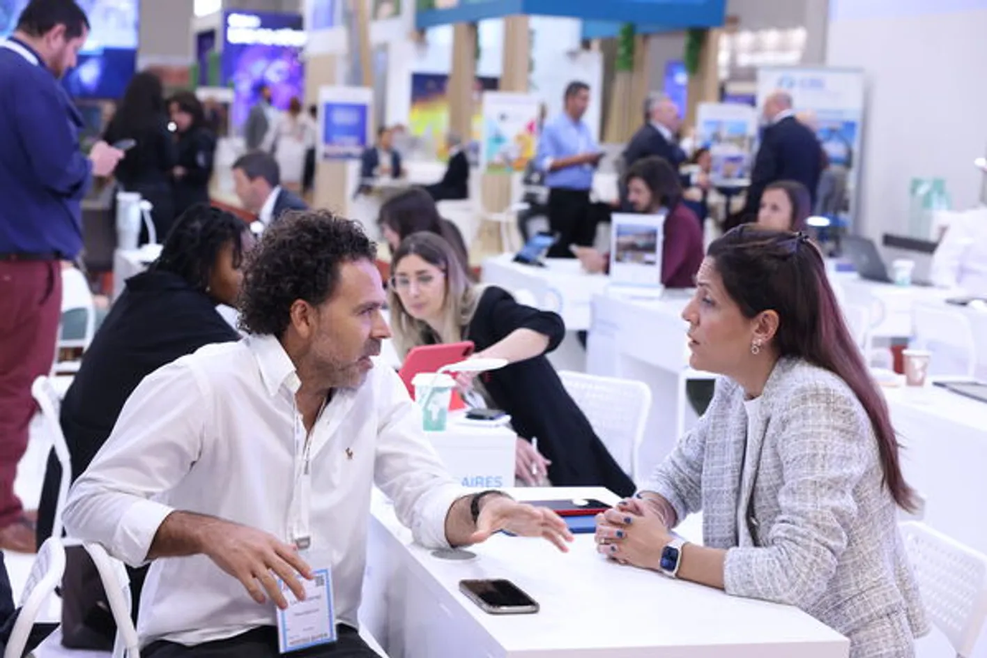 People sitting at a booth at IMEX, engaging in conversation